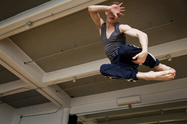 Niedriger Blickwinkel auf einen Mann in der Luft im Ballettstudio - CAVF35883