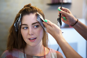 Abgeschnittenes Bild einer Frau, die einem Kunden im Salon die Haare färbt - CAVF35907