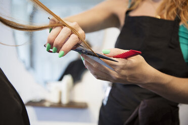 Mittelteil einer Friseurin, die einer Frau im Salon die Haare schneidet - CAVF35915