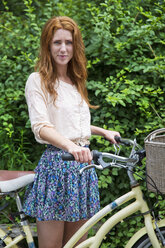 Porträt einer Frau mit Fahrrad im Park - CAVF35990