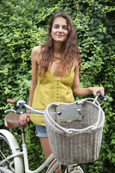 Porträt einer Frau mit Fahrrad im Park - CAVF35991