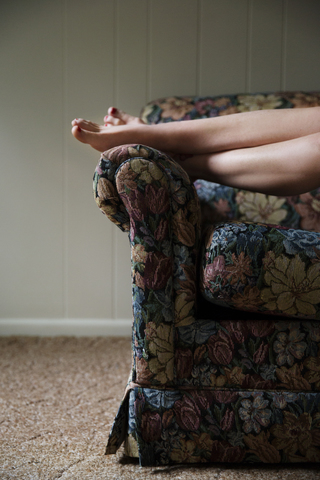 Tiefschnitt einer Frau, die sich zu Hause auf dem Sofa entspannt, lizenzfreies Stockfoto