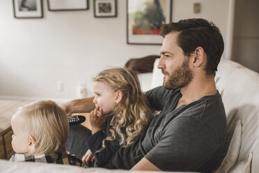 Mittlerer erwachsener Vater mit Töchtern beim Fernsehen im heimischen Wohnzimmer - MASF02295