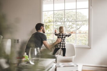 Mittlerer erwachsener Mann mit Tochter, die durch das Fenster ihres Hauses schaut - MASF02298