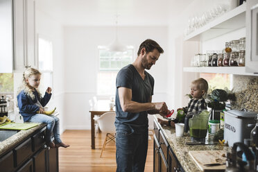 Mittlerer erwachsener Mann mit Töchtern beim Kochen in der Küche zu Hause - MASF02299