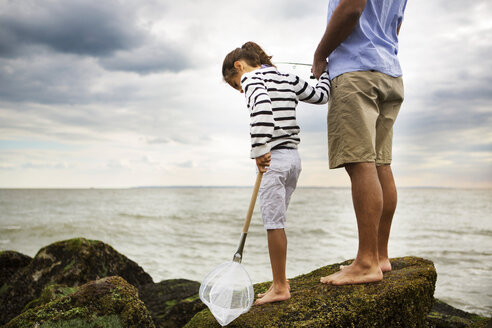 Tiefschnitt eines Mannes beim Angeln, der mit seiner Tochter auf einem Felsen am Meer steht - CAVF36170