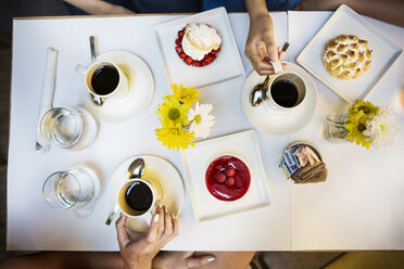 Ausgeschnittenes Bild von Freunden mit Kaffee und Dessert am Tisch im Restaurant - CAVF36204
