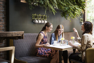 Fröhliche Freunde, die sich bei einem Kaffee am Tisch im Restaurant unterhalten - CAVF36217