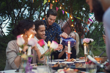 Man serving drink to friends at garden party - MASF02321