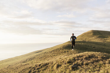 Man jogging on hill by sea during sunny day - MASF02325