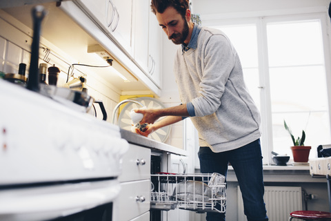 Man cleaning utensils in kitchen at home stock photo