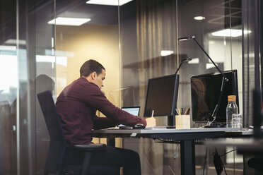 Niedriger Blickwinkel eines Geschäftsmannes, der an einem Laptop am Schreibtisch im Büro arbeitet - MASF02364