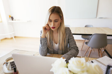 Junge Geschäftsfrau, die im Büro arbeitet und einen Laptop benutzt - EBSF02352