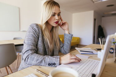 Junge Geschäftsfrau, die im Büro arbeitet und einen Laptop benutzt - EBSF02354