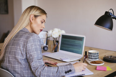 Junge Geschäftsfrau, die im Büro arbeitet und einen Laptop benutzt - EBSF02355