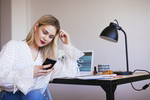 Blond businesswoman sitting at desk, working stock photo