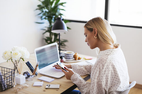 Blonde Geschäftsfrau sitzt am Schreibtisch und arbeitet - EBSF02362