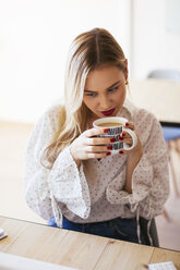 Junge Frau arbeitet im Büro, macht eine Pause, trinkt Kaffee - EBSF02363