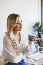 Junge Frau arbeitet im Büro, macht eine Pause, trinkt Kaffee - EBSF02367