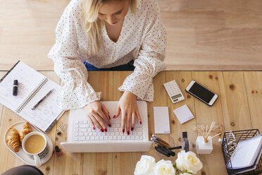 Young woman sitting at desk, using laptop - EBSF02369