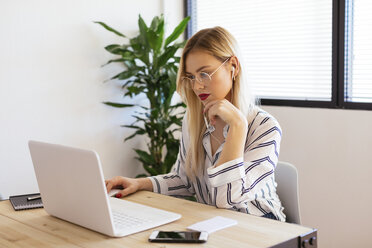 Blonder Büroangestellter sitzt am Schreibtisch und benutzt einen Laptop - EBSF02378