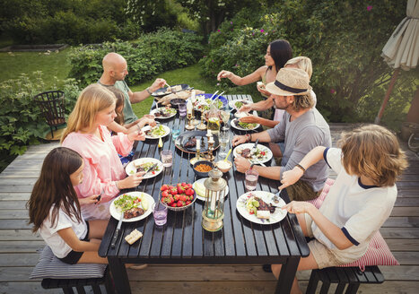 High angle view of family and friends eating lunch in back yard - MASF02373