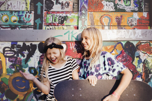 Glückliche Freunde mit Skateboards genießen gegen bunte Wand - MASF02381