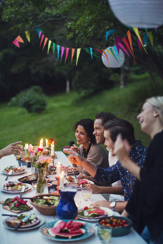 Happy friends talking while enjoying meal at garden party stock photo