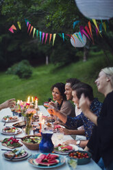 Glückliche Freunde unterhalten sich beim Essen auf einer Gartenparty - MASF02386