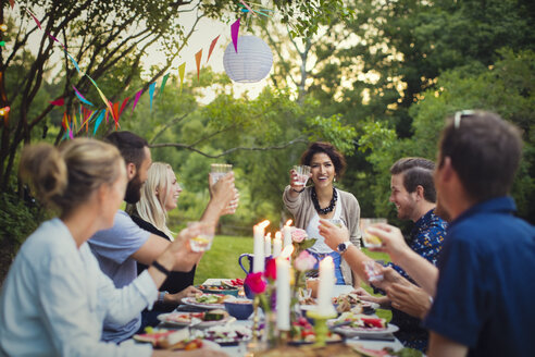 Glückliche Freunde stoßen mit Gläsern am Tisch auf eine Gartenparty an - MASF02391