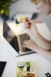 Hohe Winkel Ansicht der Geschäftsfrau mit Sushi, während mit Laptop am Tisch im Büro - MASF02403