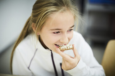 Hochwinkelansicht eines Mädchens, das während der Mittagspause in einer Cafeteria isst - MASF02405