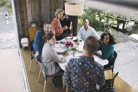 Hochformatige Ansicht von Geschäftsleuten, die in einem tragbaren Büro-LKW diskutieren, lizenzfreies Stockfoto