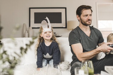 Glückliches Mädchen mit Vater und Schwester auf dem Sofa beim Fernsehen zu Hause - MASF02422