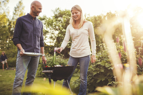 Glücklicher Vater und Tochter kochen Gemüse auf dem Grill im Hinterhof, lizenzfreies Stockfoto