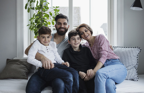Glückliche Familie sitzt auf dem Sofa im Wohnzimmer zu Hause, lizenzfreies Stockfoto