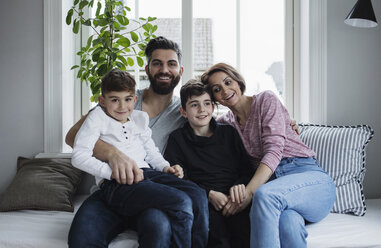 Happy family sitting on sofa in living room at home - MASF02429