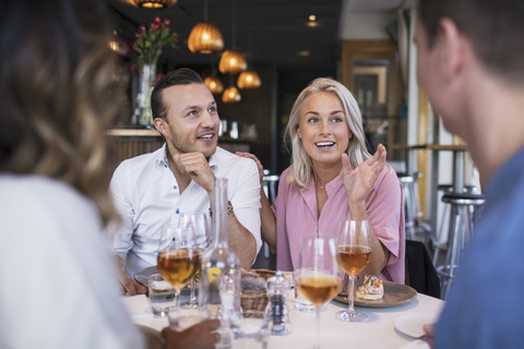 Fröhliche Kollegen unterhalten sich beim Geschäftsessen im Restaurant, lizenzfreies Stockfoto