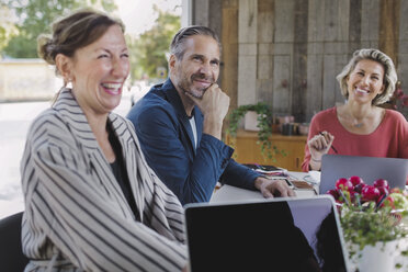 Happy businesswoman sitting with colleagues at desk in portable office truck - MASF02443