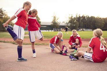 Mädchen, die sich auf dem Spielfeld die Beine vertreten, indem sie Schienbeinschoner tragen - MASF02447