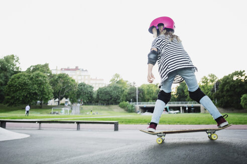 Volle Länge von Mädchen Skateboarding im Park gegen klaren Himmel - MASF02459
