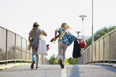 Volle Länge von Freunden halten Skateboards beim Gehen auf der Brücke gegen den klaren Himmel - MASF02462