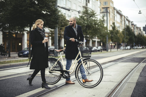 Full length of business people with bicycle crossing city street - MASF02477