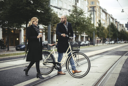 Geschäftsleute in voller Länge mit Fahrrad beim Überqueren der Stadtstraße - MASF02477