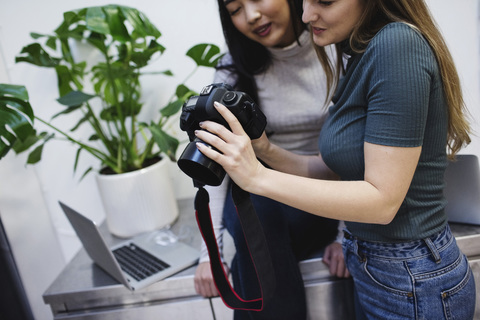 Female bloggers watching photographs on digital camera in creative office stock photo