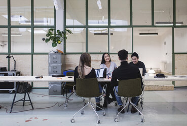 Vier Menschen diskutieren am Schreibtisch in einem kreativen Büro - MASF02489