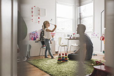 Vater betrachtet Töchter beim Spielen mit Spielzeug im Spielzimmer zu Hause - MASF02499