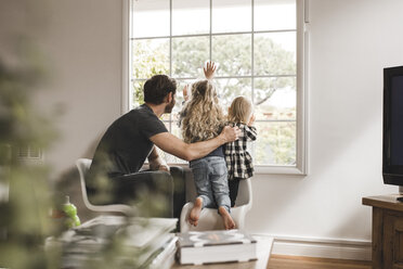 Father with daughters looking through window at home - MASF02502