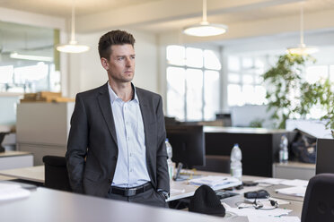 Portrait of a successful businessman standing in office, looking serious - DIGF03902