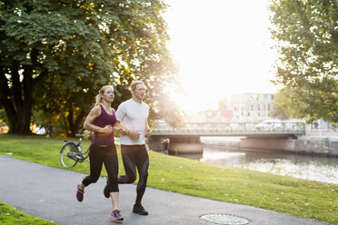 Paar joggt auf dem Fußweg im Park bei Sonnenaufgang - MASF02509